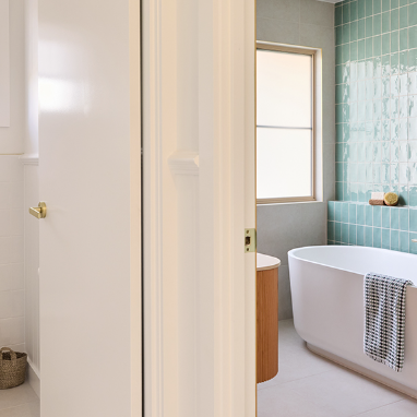 Modern bathroom with round mirror, wooden vanity, and white sink.